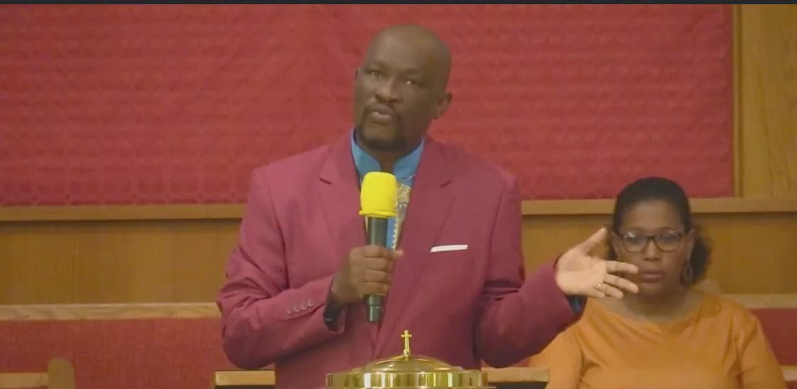 Pastor Jeudy preaching from the pulpit with interpreter